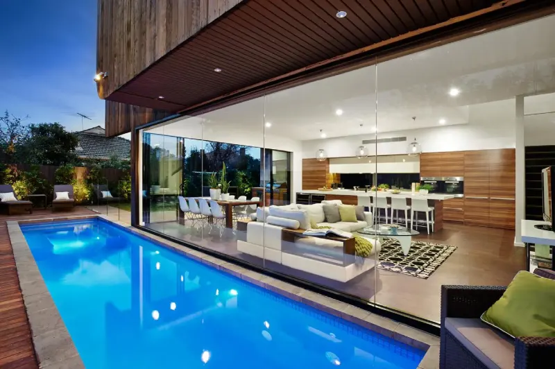 Residential lap pool alongside an open-plan living and kitchen space with timber cladding